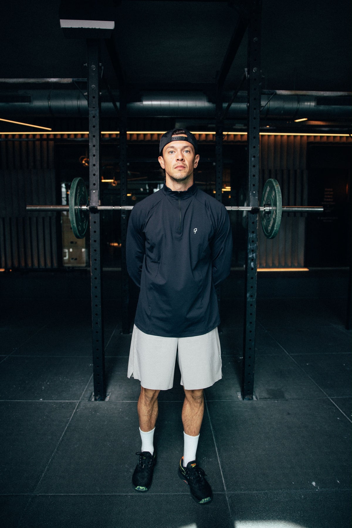 Man draagt Fract longsleeve Ash Black tijdens training, gym op de achtergrond